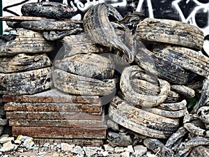 Stacked old tires with rusty metal base in urban setting