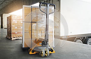 Stacked of Package Boxes on pallet with Hand Pallet Truck. Trailer Truck Parked Loading at Dock Warehouse. Cargo Shipment Boxes.