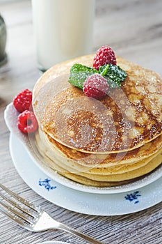 Stacked pancakes raspberries mint sugar milk