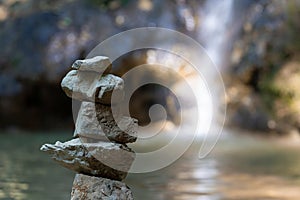 Stacked pile of stones in front of reflecting lake and cascade. Scenie for meditation concept. Biggest waterfall of canton Aargau