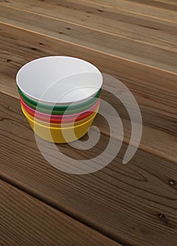 Colorful plastic bowls on wood background.