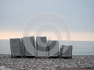 Stacked plastic sun loungers on the beach. Sunbeds in bad weather. Resort in off season