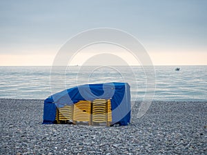 Stacked plastic sun loungers on the beach. Sunbeds in bad weather. Resort in off season