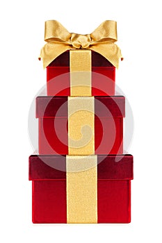 Stacked red gift boxes wrapped with shiny gold bow and ribbon isolated on white