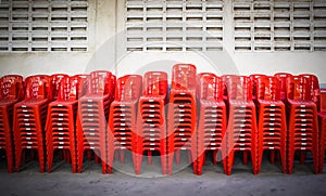 Stacked red plastic chairs in rows