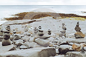 Stacked rocks into a standing still formation, pebbles by the beach put one on another as hihg as possible, groups of stones in