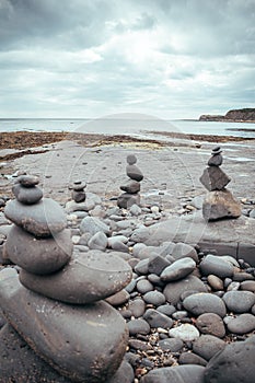 Stacked rocks into a standing still formation, pebbles by the beach put one on another as hihg as possible, groups of stones in