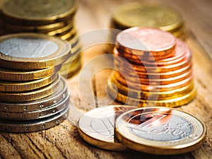 Stacked shiny white and golden Euro coins of different value on wood background, finances, investment, stock, savings concept