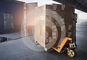 Stacked of shipments boxes on pallet with hand pallet truck waiting for load into a truck. Road freight cargo industry.