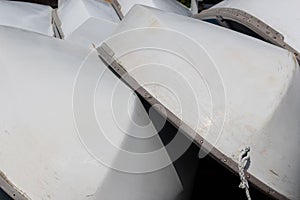 Stacked small sailboats, white hulls with metal trim