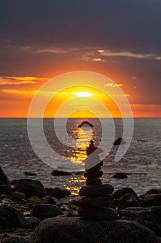 Stacked stones on a coast at orange sunset