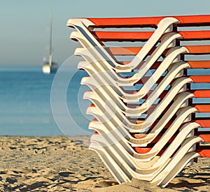 Stacked sun beds on a sandy beach at sunrise