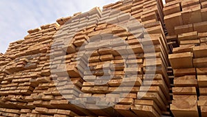 Stacked Timber Planks at a Lumberyard Awaiting Transportation. Stacked wooden planks in varying shades of brown at a