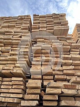 Stacked Timber Planks at a Lumberyard Awaiting Transportation. Stacked wooden planks in varying shades of brown at a