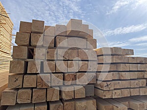 Stacked Timber Planks at a Lumberyard Awaiting Transportation. Stacked wooden planks in varying shades of brown at a