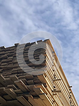 Stacked Timber Planks at a Lumberyard Awaiting Transportation. Stacked wooden planks in varying shades of brown at a