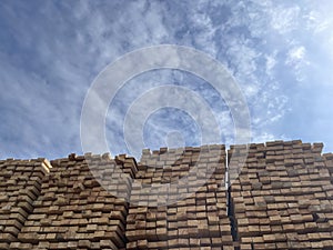 Stacked Timber Planks at a Lumberyard Awaiting Transportation. Stacked wooden planks in varying shades of brown at a