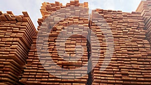 Stacked timber planks at a lumberyard awaiting transportation. Stacked wooden planks in varying shades of brown at a