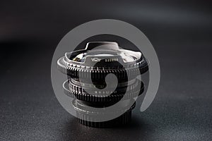 Stacked vintage camera lenses with a focus on the serial number, reflective glass surface, photography tools against a