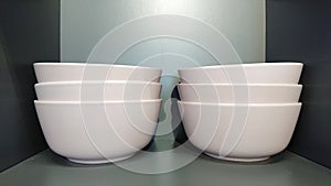 Stacked white ceramic bowls on shelf