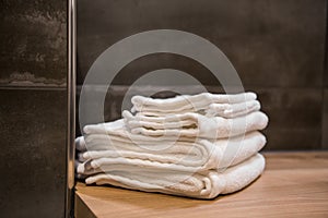 Stacked white spa towels on wooden table at modern bathroom