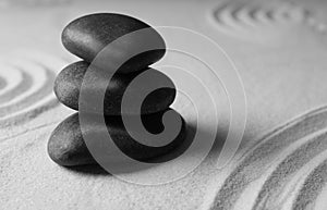 Stacked zen garden stones on sand with pattern, space for text.