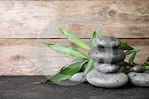Stacked zen stones and bamboo leaves on table against wooden background