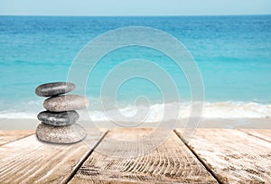 Stacked zen stones on wooden pier against sea