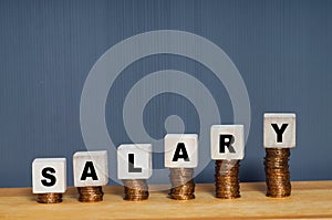 Stacking coins with salary word on wooden block