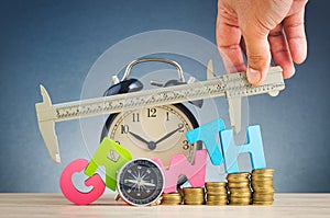 Stacking coins and word GROWTH on wooden desk over beautiful reverberation gradient background