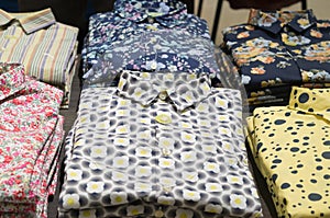 Stacking shirts with colorful pattern on sale in orderly piles in department store