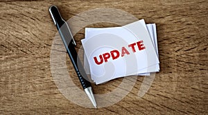 Stacking of UPDATE text on white business card with a elegance pen on wooden background