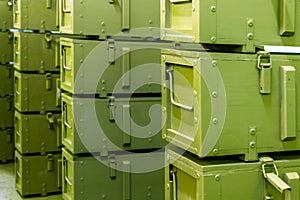 Stacks of abstract green military crates without any markings - close-up with selective focus and background blur