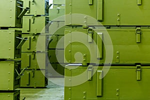 Stacks of abstract green military crates without any markings - close-up with selective focus and background blur