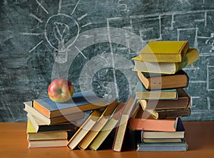 stacks of books in front of black board and red apple.Back to school, education is power,research, learning concept, free copy