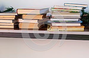 Stacks of books on table near white wall