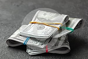 Stacks of cash dollars tied with colored office bands on dark background. Concept of savings or bribe