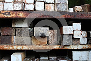 Stacks of ceramic kiln bricks on rusted metal shelves