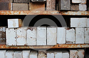 Stacks of ceramic kiln bricks on rusted metal shelves