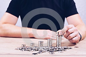 Stacks of coins in ascending order. Wealth. A man's hand puts coins. Investments and accumulation of dollars and euros