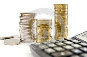 Stacks of coins and a calculator on a white background. Concept of savings, taxes or economy.