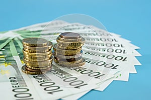 Stacks of coins and 100 euros on a blue background. Concept of savings, economy