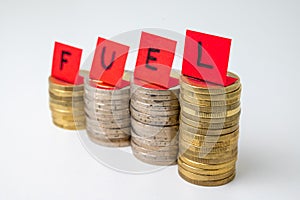 Stacks of coins and `fuel` text. Rising fuel prices