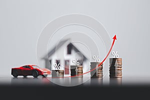 Stacks of coins and model house and car with percentage symbol for increasing interest rates. Interest rate financial and mortgage