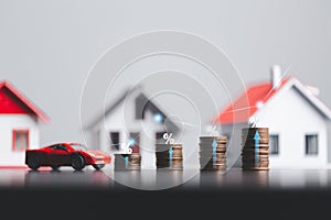 Stacks of coins and model house and car with percentage symbol for increasing interest rates. Interest rate financial and mortgage