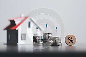 Stacks of coins and model house with percentage symbol for increasing interest rates. Interest rate financial and mortgage rates.