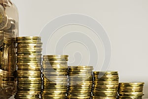 Stacks of Coins next to a jar full of coins