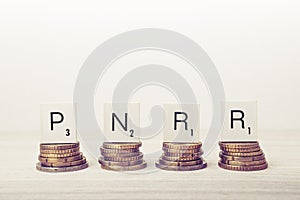 Stacks of coins with PNRR letters. UE economy concept.