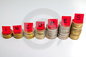 Stacks of coins and text `incomes`. Increase in revenue and earnings.