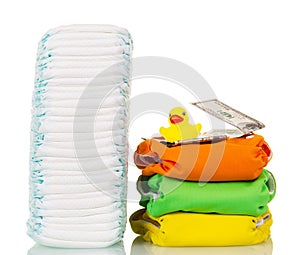 Stacks disposable and cloth diapers, money, rubber duck isolated. photo